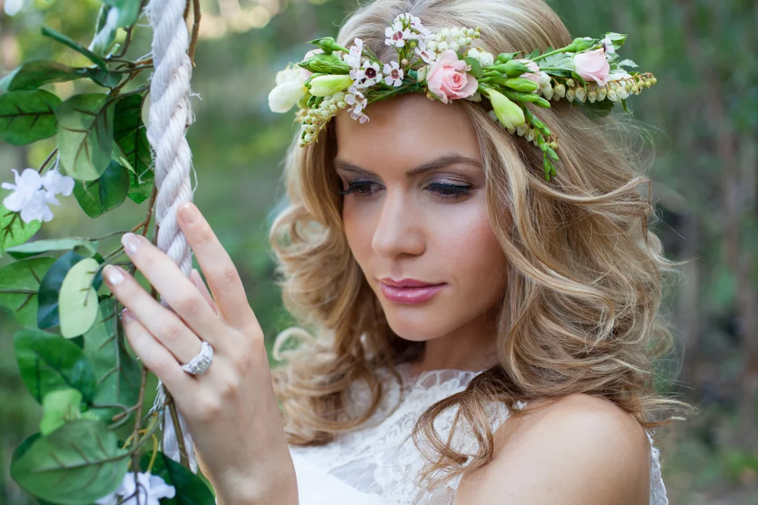 Soft bridal makeup with defined eyes and pink lips, paired with a floral crown