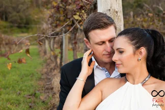 Bride with softly defined eye makeup and a sleek ponytail embracing her partner